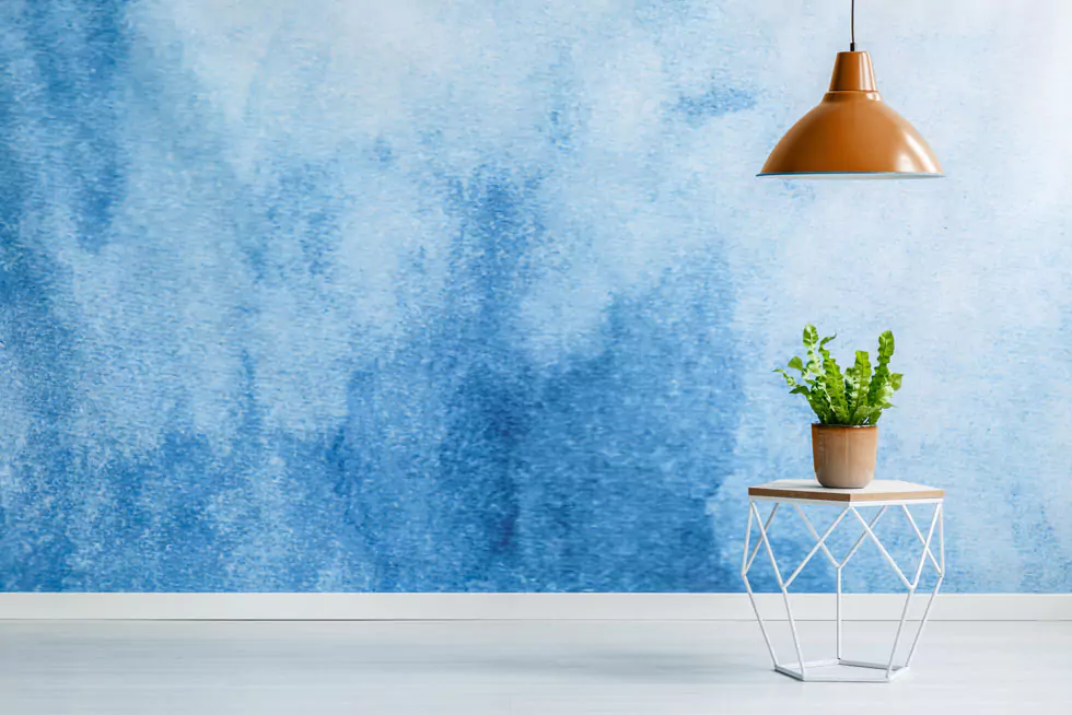 valpaint Lampe über einem modernen Tisch mit Pflanze vor einer blauen Wand mit Valpainteffekten