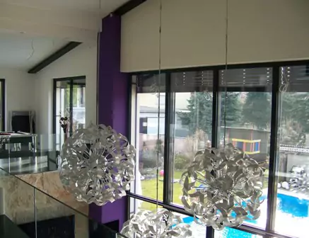 Moderner Wohnraum mit großen Glasfronten, violettem Wanddetail und auffälligen Designer-Lampen.