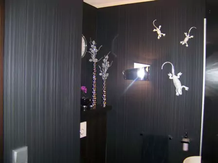 Kleines Bad mit dunklen Wandflächen, silberner Wanddeko aus Metallgeckos und moderner Beleuchtung.