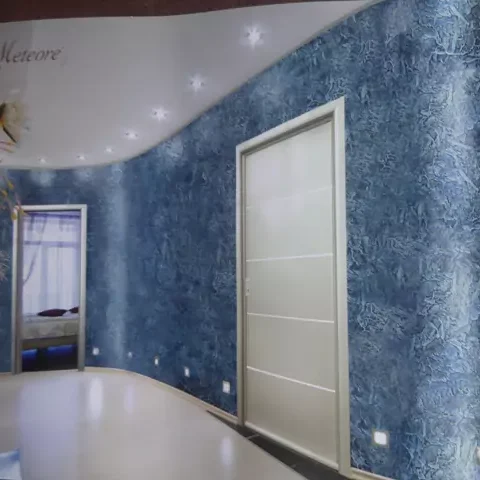 Lampe über einem modernen Tisch mit Pflanze vor einer blauen Wand mit Valpainteffekten