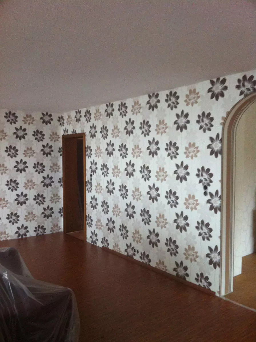 Heller Wohnraum mit auffälliger Blumentapete in Beige und Schwarz als Blickfang.