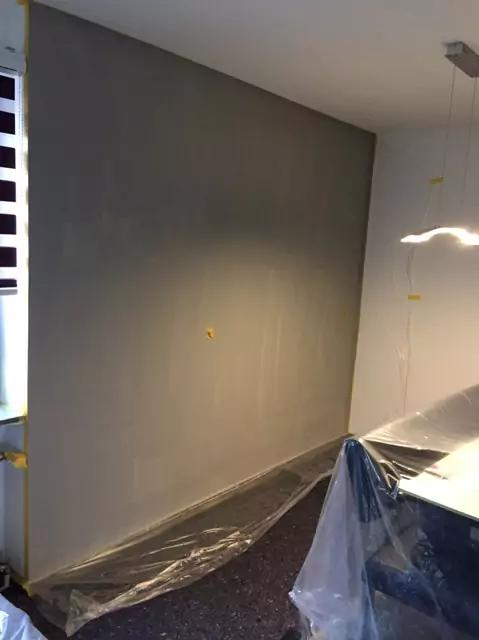 Glatt verputzte, graue Wandfläche im Wohnraum, vorbereitet für kreative Wandgestaltung.