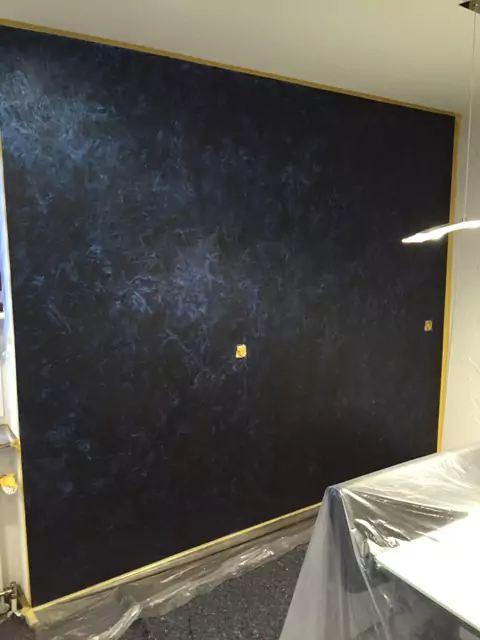 Kreative Wandgestaltung mit blauer Strukturtechnik auf dunklem Untergrund im Wohnraum.
