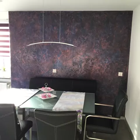 Modernes Esszimmer mit auffälliger Effektwand in Rot-Schwarz und Glas-Esstisch.