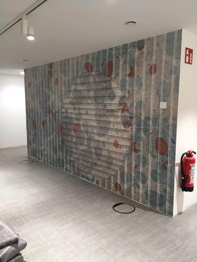 Auffällige Tapete mit kreisförmigem Muster in Blau und Rot auf strukturierter Wand.