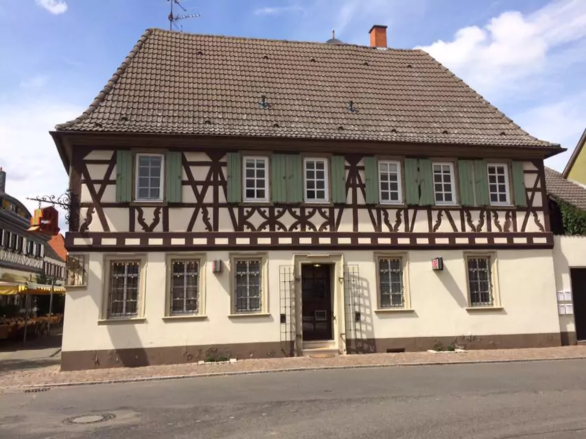 Altes Fachwerkhaus mit braunen Balken und grünen Fensterläden vor einer umfassenden Sanierung.