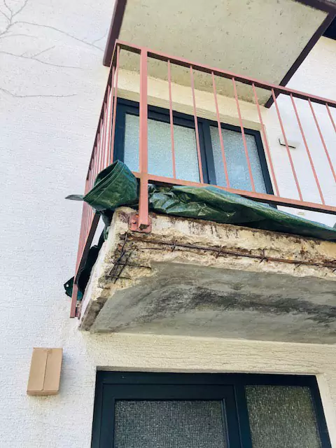Blick von unten auf einen Balkon mit Metallgeländer während der Sanierung