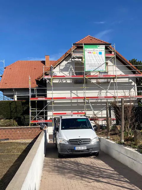 Wohnhaus mit Baugerüst und Casa Colore Firmenwagen bei Fassadenrenovierung.