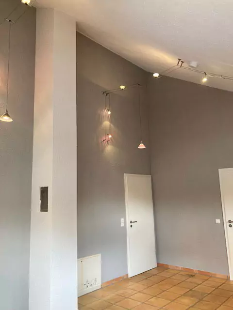 Blick in einen grau gestrichenen hohen Raum im Altbau mit dekorativen Deckenlampen
