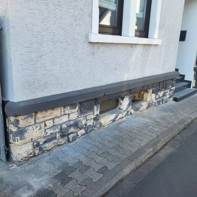 Blick auf den vergilbten und verdreckten Sockelbereich Hauses vor der Sanierung