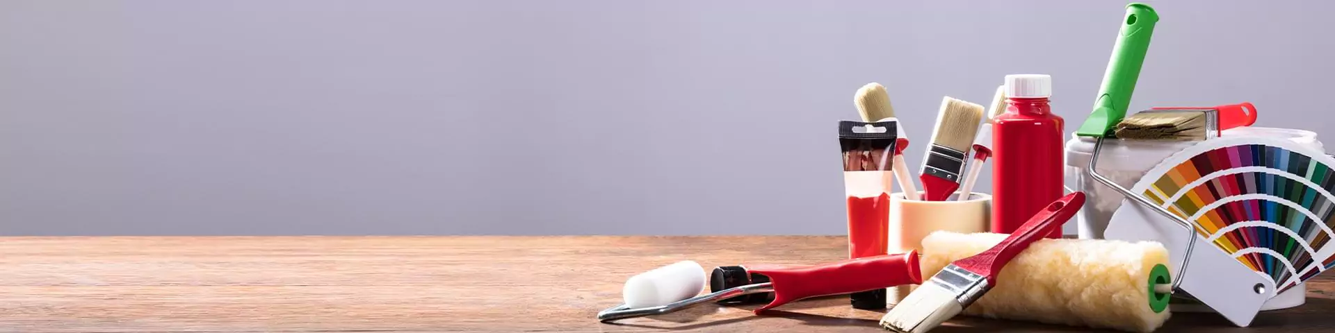 Malerutensilien (Pinsel, Farben, Farbrollen, Farbfächer) auf einem Holz